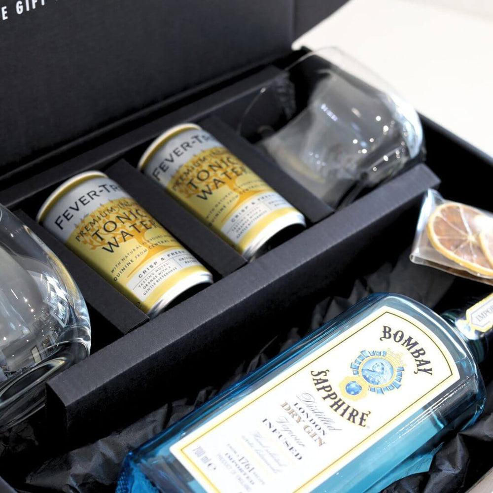 Gin and tonic set with Bombay Sapphire gin, tonic water cans, and glasses in a black gift box.